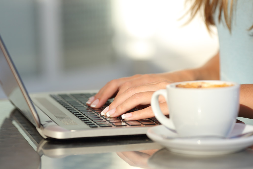 Woman hands typing in a laptop in a coffee shop