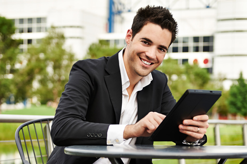 Young successful businessman with tablet outdoors